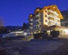 Veľká budova hotela v horskej oblasti počas súmraku, osvetlená umelými svetlami.