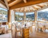 Reštaurácia s prestretými stolmi a výhľadom na zasnežené hory.