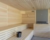 Interiér modernej sauny s drevenými lavicami a kovovým vedrom.