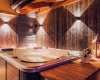 Vnútorná jacuzzi obklopená drevenými panelmi s osvetlením a lampášom na stole.