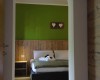 Izba s posteľou, zelenou stenou a dreveným obkladom, nad ktorým visí dekorácia so srdiečkami.