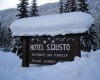 Drevená tabuľa hotela S. Giusto pokrytá snehom v zimnej krajine.