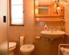 Kúpeľňa so sprchovým kútom, umývadlom, zrkadlom, bidetom a WC v teplých tónoch.  