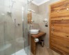 Malá kúpeľňa so skleneným sprchovacím kútom a drevenými prvkami.