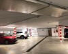 Podzemná garáž s autami a stĺpmi s červeno-bielymi pruhmi.