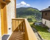Balkón s výhľadom na horskú krajinu s modrou oblohou a oblakmi.