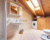 Podkrovná kúpeľňa s umývadlom, práčkou a strešným oknom.
