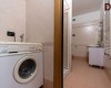 Práčovňa s práčkou vedľa kúpeľne s umývadlom a radiátorom.  