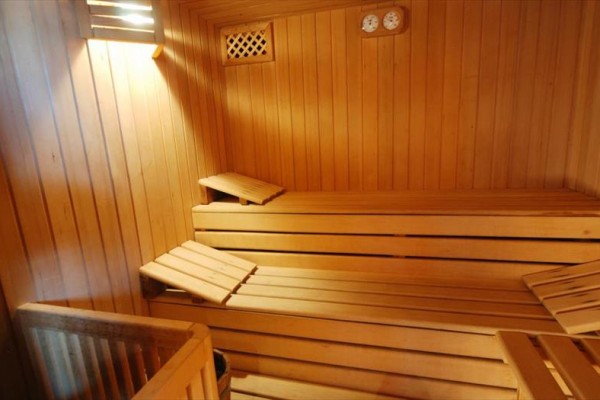Drevená sauna s lavičkami a meradlami na stene.