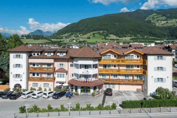 Veľký hotel s parkoviskom a horami v pozadí.