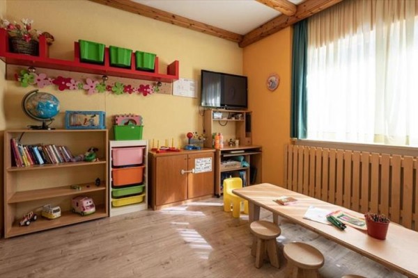 Detská izba s nábytkom, hračkami a oknom s polopriehľadnými závesmi.