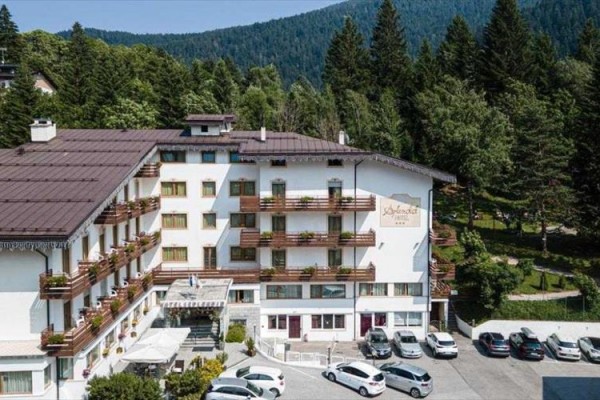 Hotel obklopený lesmi s parkoviskom plným áut.