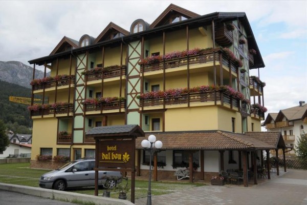 Hotel s drevenými balkónmi plnými kvetov.