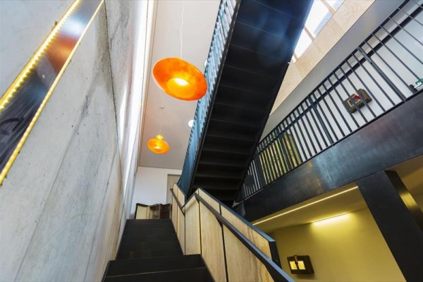 Moderný interiér s čiernym schodiskom a oranžovými lampami.  