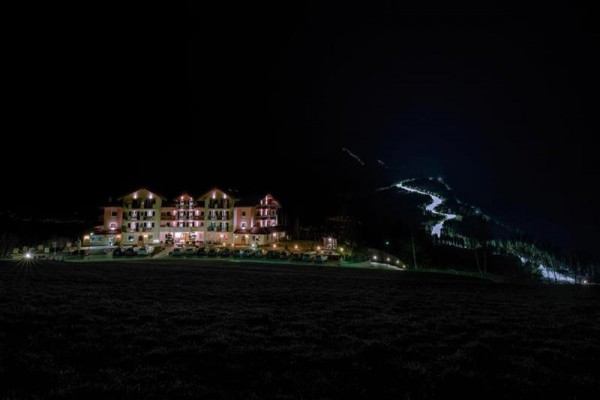 Nočný osvetlený hotel pri svahu s osvetlenou cestou.