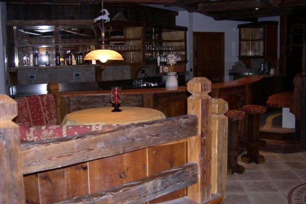 Drevený bar s okrúhlym stolom a stoličkami v horskom štýle.