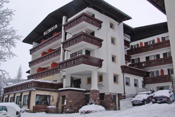 Hotel s drevenými balkónmi pokrytý snehom.