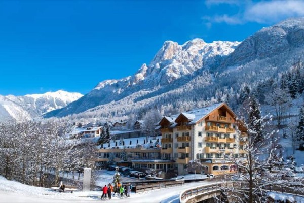 Hotel v zasneženej horskej krajine s jasnou modrou oblohou.