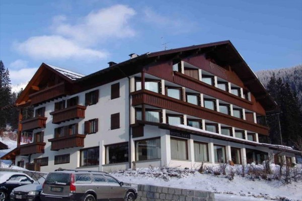 Horský hotel s drevenými balkónmi a zasneženou strechou.