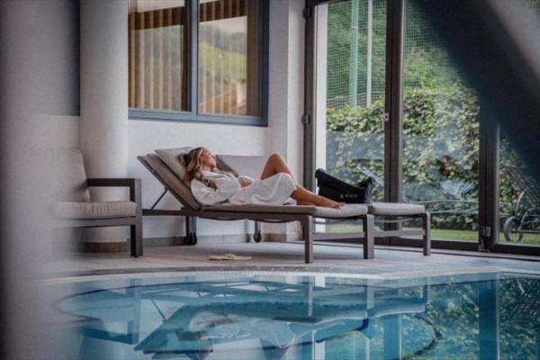 Žena relaxuje na lehátku pri vnútornom bazéne.