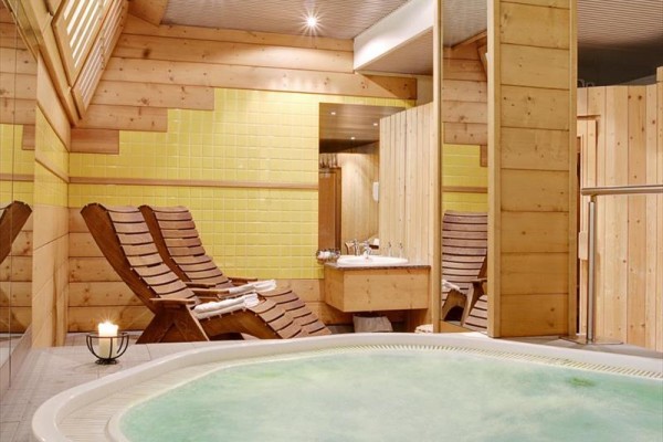 Luxusný wellness s drevenými lehátkami a vírivkou.