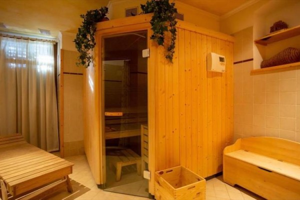 Drevená sauna v útulnej miestnosti s ležadlom.