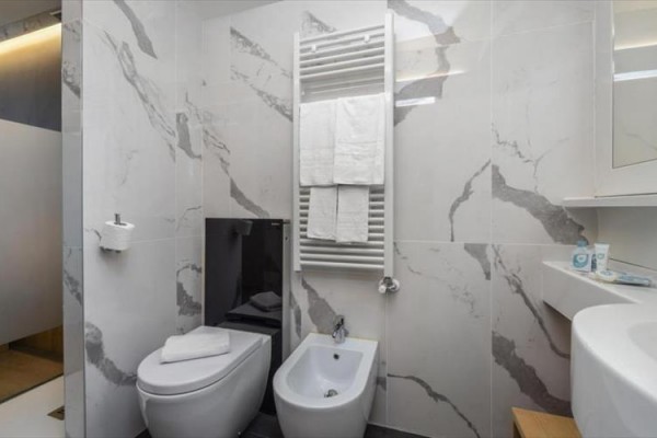 Luxusná kúpeľňa s mramorovými obkladmi, WC a bidetom.