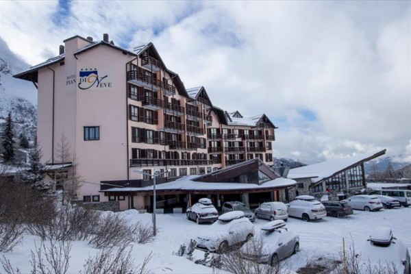 Hotel v zasneženej krajine s parkoviskom plným áut.