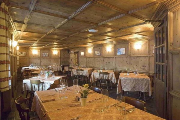 Tradičná drevená jedáleň s pripravenými stolmi na večeru.