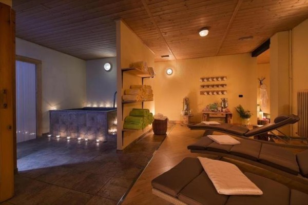 Relaxačná miestnosť s ležadlami, uterákmi a vírivkou osvetlená tlmeným svetlom.  