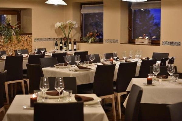 Luxusná reštaurácia s elegantne prestretými stolmi a fľašami vína.