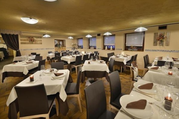 Štýlová reštaurácia s drevenými stolmi, hnedými stoličkami a prestretými stolmi.