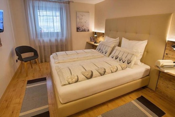 Moderná spálňa s manželskou posteľou a oknom.