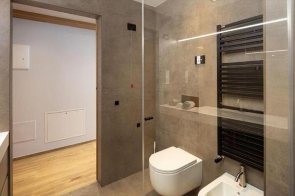Moderná kúpeľňa s toaletou, bidetom a sklenenými dverami.
