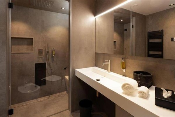 Moderná kúpeľňa s veľkým zrkadlom, sprchovým kútom a umývadlom so svetlou doskou.