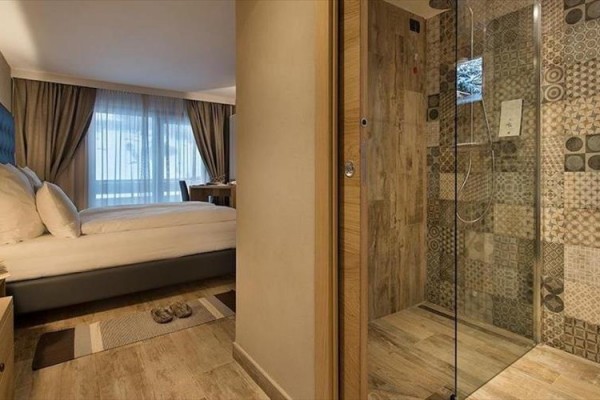 Hotelová izba s manželskou posteľou a preskleným sprchovacím kútom.