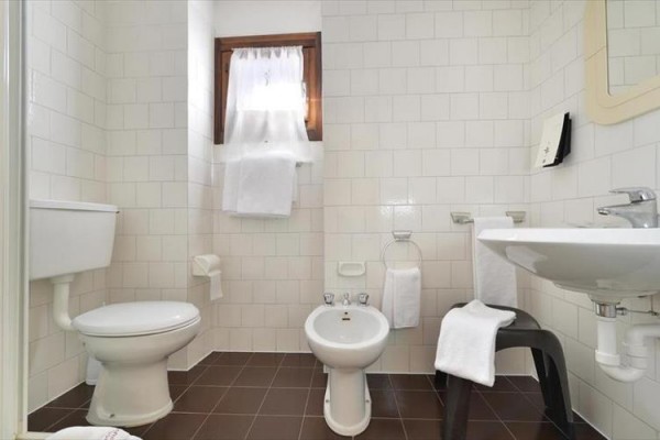 Kúpeľňa s toaletou, bidetom, umývadlom a malým oknom.