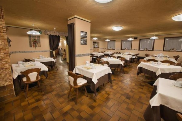 Stoly s bielymi obrusmi v prázdnej reštaurácii.