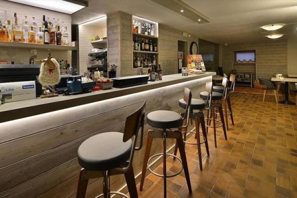 Moderný bar s vysokými stoličkami a fľašami na polici.