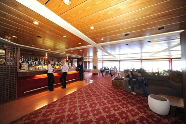 Luxusný hotelový bar s personálom a hosťami relaxujúcimi na pohovkách.