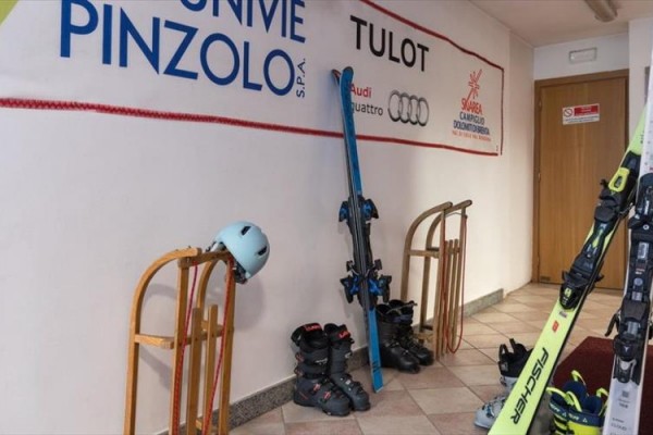 Lyžiarska výstroj je opretá o stenu s reklamnými bannermi.