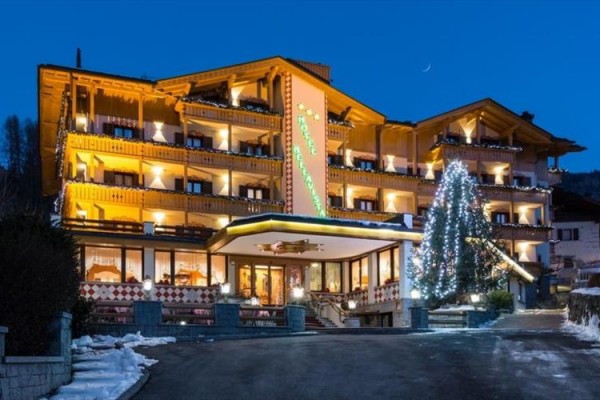 V noci osvetlený horský hotel s vianočnými dekoráciami.
