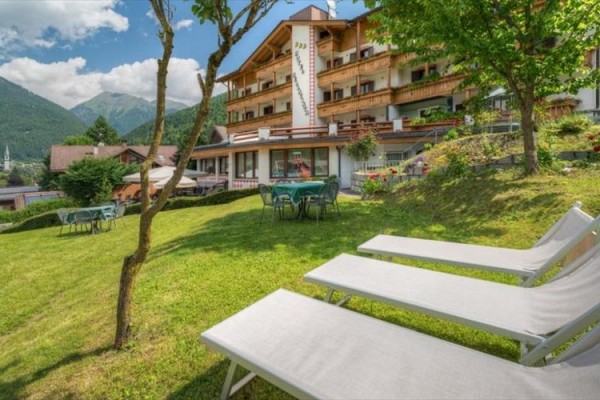 Hotel s ležadlami a stolmi na trávniku v horskej krajine.