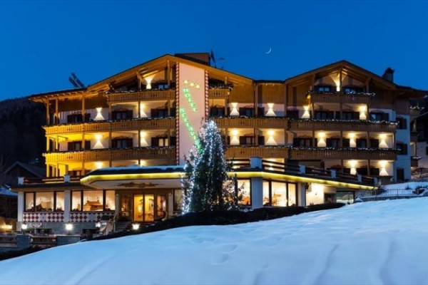 Hotel so svetlým dreveným obložením a osvetlením v zasneženej krajine pri súmraku.