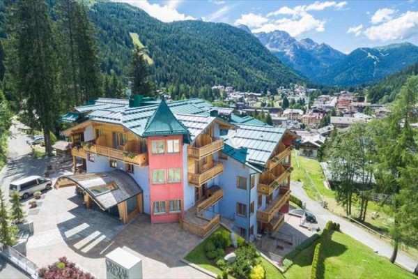 Hotel obklopený horami a lesmi za slnečného dňa.