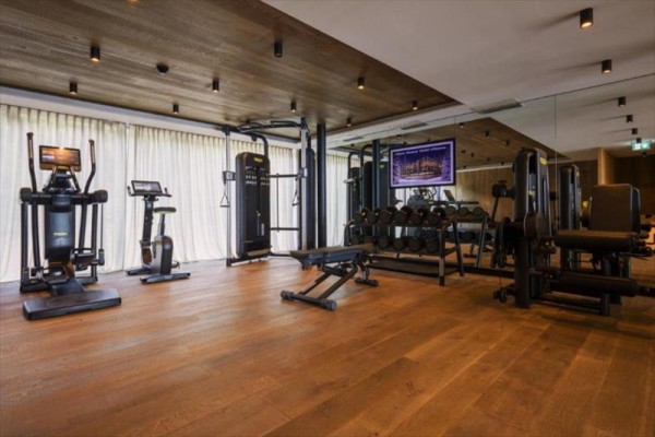 Moderné fitness centrum s rôznym cvičebným vybavením na drevenej podlahe.
