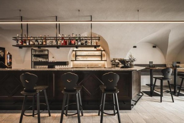 Štýlový bar s vysokými stoličkami a policami s fľašami alkoholu.