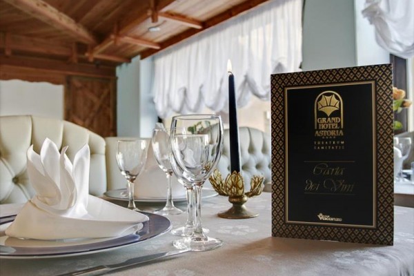 Elegantne prestretý stôl v hotelovej reštaurácii s podnosom, pohármi a sviečkou.  