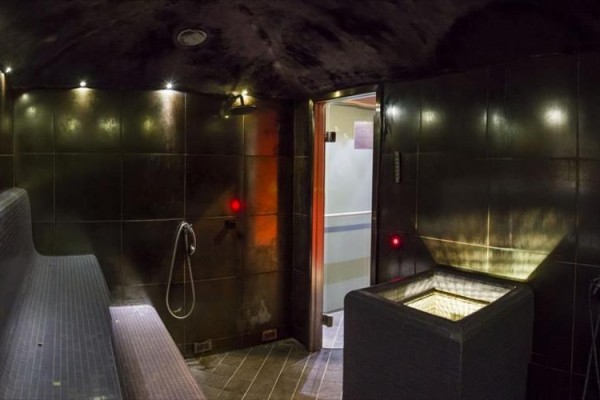 Moderná parná sauna s lavicou, osvetlením a dverami do ďalšej miestnosti.