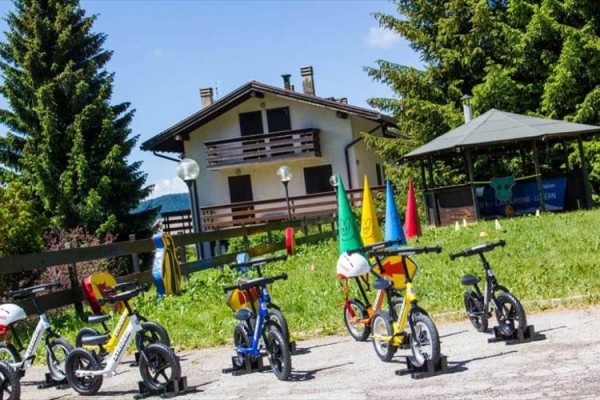 Detské bicykle zoradené pred domom a altánkom v záhrade.